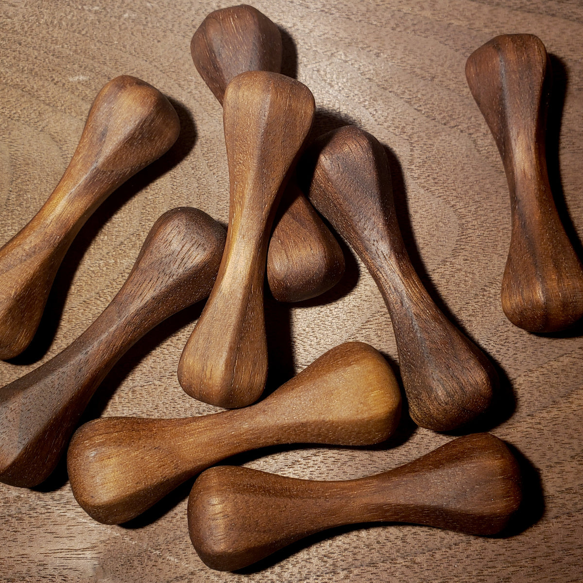 A group of dark walnut knuckle roller pocket sculptures.
